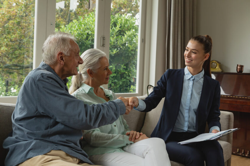 Active senior man shaking hands with real estate agent in living room